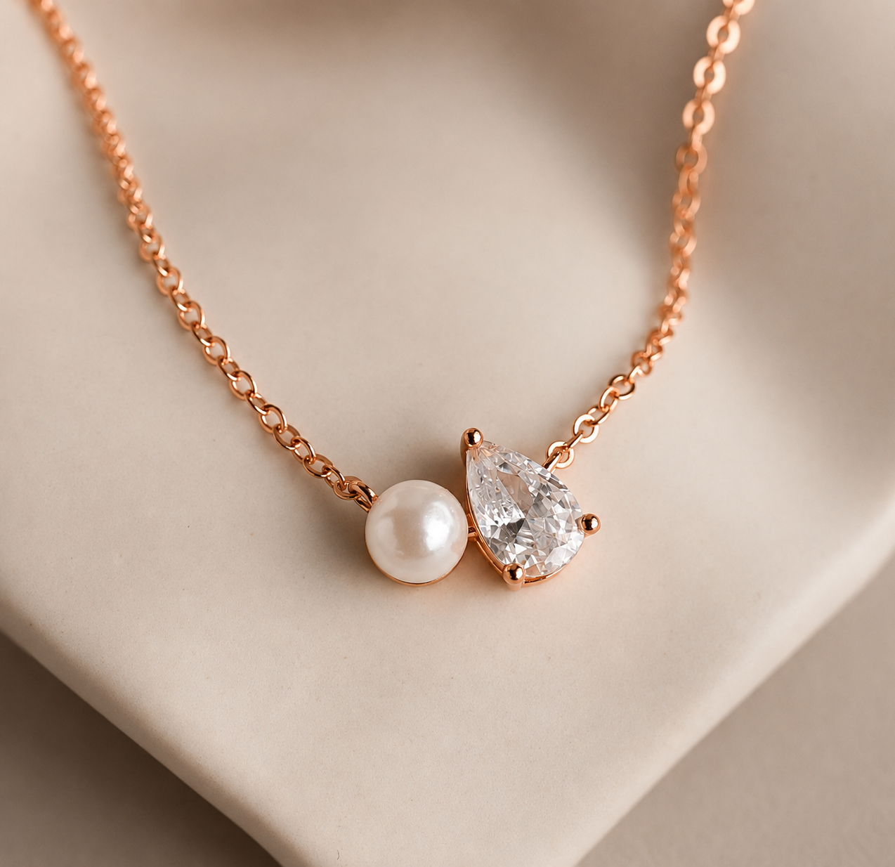 Necklace with a teardrop-shaped diamond and pearl pendant on a beige background
